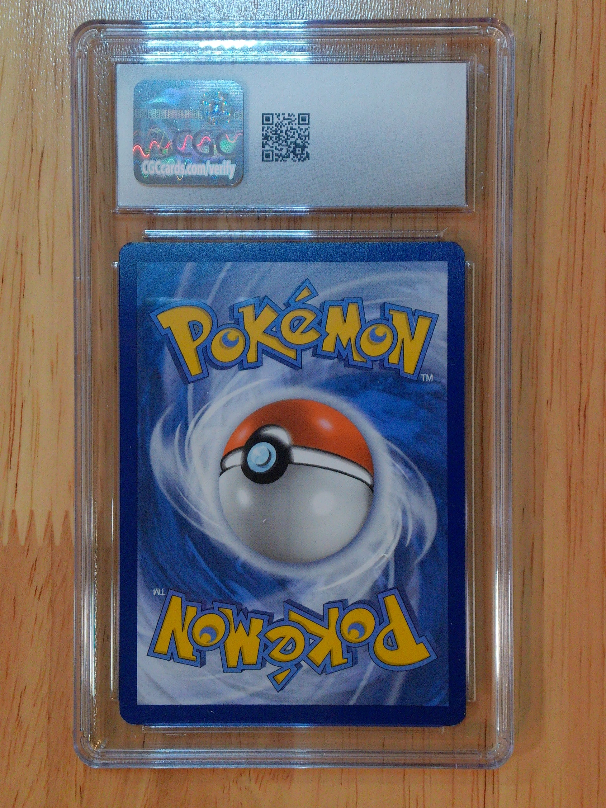 Pokémon trading card in a clear protective case on a wooden surface